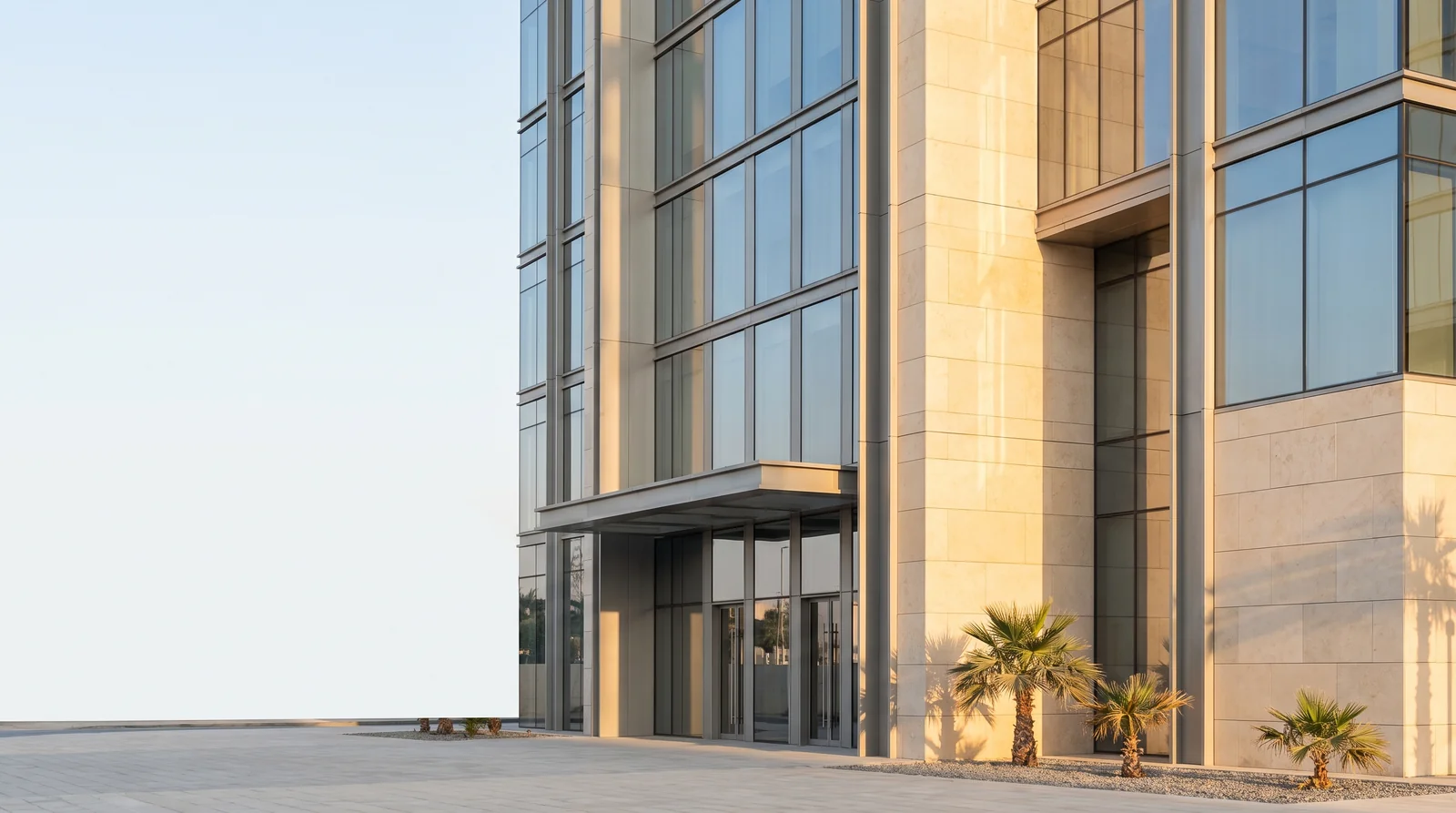 A modern free zone office tower in warm early morning light, seen from street level.
